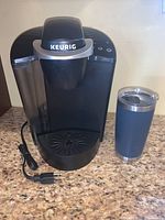 Photo of Keurig coffee maker and Yeti tumbler side by side on kitchen counter.