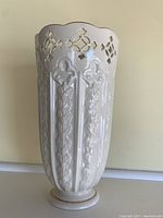 Full view of vase showing scalloped rim with pierced fleur de lis pattern and vertical embossed floral motifs