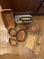 Top view showing nine baskets including two Longaberger baskets, a carved wooden pineapple, round wooden bowl, and other woven baskets.