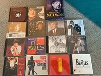 Full overview of all 16 CDs showing album covers featuring artists Rod Stewart, Willie Nelson, The Beatles, Shirley Horn, Bruce Springsteen, The Rolling Stones, Gloria Estefan