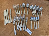 Full overhead photo of flatware showing all knives, forks, spoons, and serving spoons included in the set.