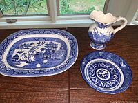 Set of 3 items on table near window: large blue willow platter, bowl, and pitcher.