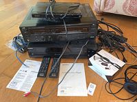 Lot components arranged on floor: JVC stereo receiver, Sony 5-CD changer, Sony DVD player, various cables, two Sony remotes, manuals, and Radio Shack IR repeater headset and box.