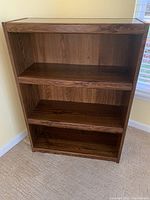 Front view of solid wood 3-shelf bookcase showing thickness and wood grain finish.