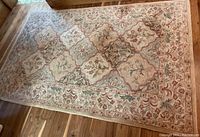 Full view of the wool area rug spread on a wooden floor, showing overall pattern and condition.