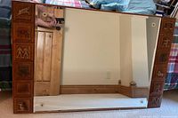 Full view of mirror on floor showing wood frame with zodiac carvings