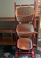 Photo of a wooden frame with three hanging woven baskets in wicker material.
