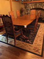 Full set showing wooden dining table, two armchairs, four side chairs, and floral patterned rug beneath.