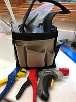Small tool bag with electrical tools including wire strippers and cordless drill inside and outside