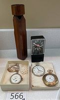 Photo showing two Elgin pocket watches in boxes, Sheffield-Timer alarm clock, wooden whistle, and three polished stones including a shell and metallic heart shape