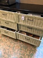 Drawer with partially opened compartments showing assortment of kitchenware including baskets and other items.
