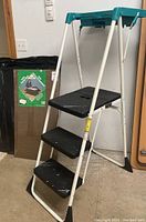 Foldable 3-step stool standing open with visible black steps and teal handle