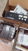 Wide view of both Tascam units in original boxes with packing foam and manuals