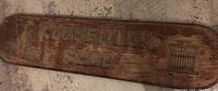 Wooden Carpenter Shop sign showing carved text and images on wood surface with aged texture.