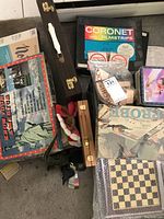 Photo showing assortment of various board games and game sets including filmstrips, checkers/backgammon cases, Probe game, and small figurines