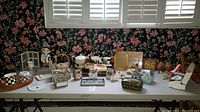 Overview of entire lot on folding table against floral wallpaper including tea set pieces, decorative boxes, music boxes, figurines.