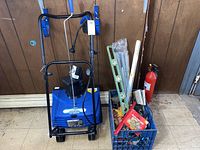 Front and handle of blue electric snow thrower with power cord, showing its compact design and controls