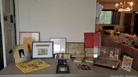 View showing all frames and pictures arranged together on table with living area in background