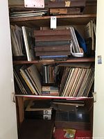 Shelf with assorted vintage vinyl records in worn sleeves and cases, stacked vertically and horizontally