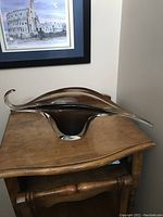 Front view of smoke glass centrepiece showing sleek flowing form and black-brown tint.