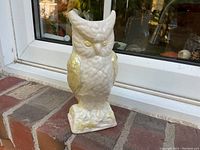 Front view of the owl vase showing the textured off-white body and yellow iridescent wings and eyes.