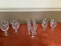 Overall view of crystal glasses in Cross and Olive pattern including chalices, sherbet and aperitif glasses arranged on table.