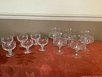 Wide view of the complete set showing 6 champagne and 5 dessert goblets on a reddish tablecloth.