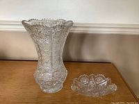 Photograph of vintage Czechoslovakian cut glass vase with flared scalloped top and raised detailed cuttings, standing next to matching trinket dish with starburst and geometric cut pattern.