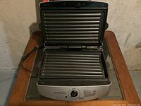Open electric grill/panini press showing removable ribbed grill plates.
