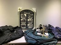 Photo showing the entire lot including the framed 'End Of An Era The Original Six Arenas' placard still in original protective wrapping, Bauer Supreme size 10 men's hockey skates with yellow laces, and three different bags: a black Bovano bag, a green Nike hockey bag, and a blue Eddie Bauer EBTEK shoulder bag.