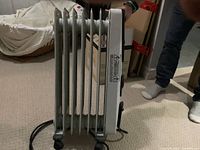 Side view of white Kenwood oil-filled radiator heater showing metal fins and control housing at the side with power cord visible.