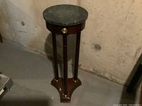 Full front view of round marble top table showing marble surface and wooden base