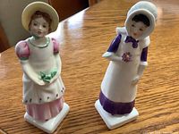 Two Royal Doulton Kate Greenaway figurines, Emma and Anna, standing on wooden surface, front view