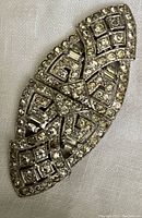 Photo of a large leaf-shaped rhinestone dress clip with geometric pattern.