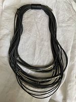 Full view of necklace with multiple black rubber cords and magnetic clasp