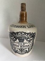 Front view of whiskey jug showing label text 'Cruiskeen Lawn Mitchell's Old Irish Whiskey Belfast' and cork stopper.