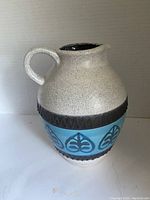 Front and side views of the Midcentury Dumler and Breiden jug showing blue and beige ceramic with chocolate brown textured bands and leaf motif.