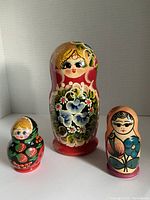 Three Russian nesting dolls in different sizes and designs shown separately.