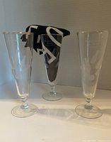 Three clear etched glasses each with O'Connor Bowl Toronto and bowling pins and ball design, standing side by side with a black and white cloth behind.