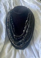 Full front view of the 7 strand black buffalo bead necklace on display stand showing layered strands of beads
