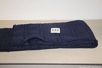 Folded navy blue weighted blanket with visible quilted square segments and tag number 122