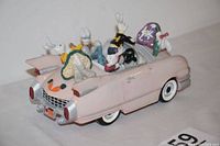 Rear and side view of pink Cadillac with five rabbit figurines, showing tail lights, license plate with heart, and one missing side mirror.