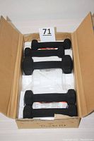 Five rubber coated dumbbells arranged inside an open cardboard box, showing different sizes.