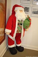 Front-side view of Santa Claus figure showing full costume, beard, and sack with gift props.