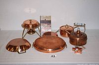 Photo showing all seven kitchen items arranged with fondue base, pots, pans, kettle, cutter, and fondue book visible.