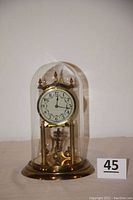 Front view of the torsion pendulum anniversary clock under glass dome with brass base.
