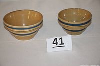Front angle showing both yellowware bowls with blue and white stripes, placed side by side.