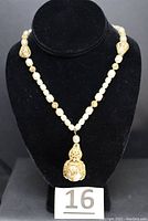 Necklace displayed on black bust showing overall design and strand arrangement