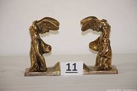 Photo showing front view of the pair of bronze Winged Victory of Samothrace bookends, placed side by side with a label '11' between them.