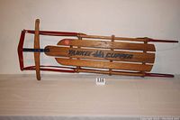 Full length top view of the wooden and steel Yankee Clipper sled showing the slatted seat and metal frame.